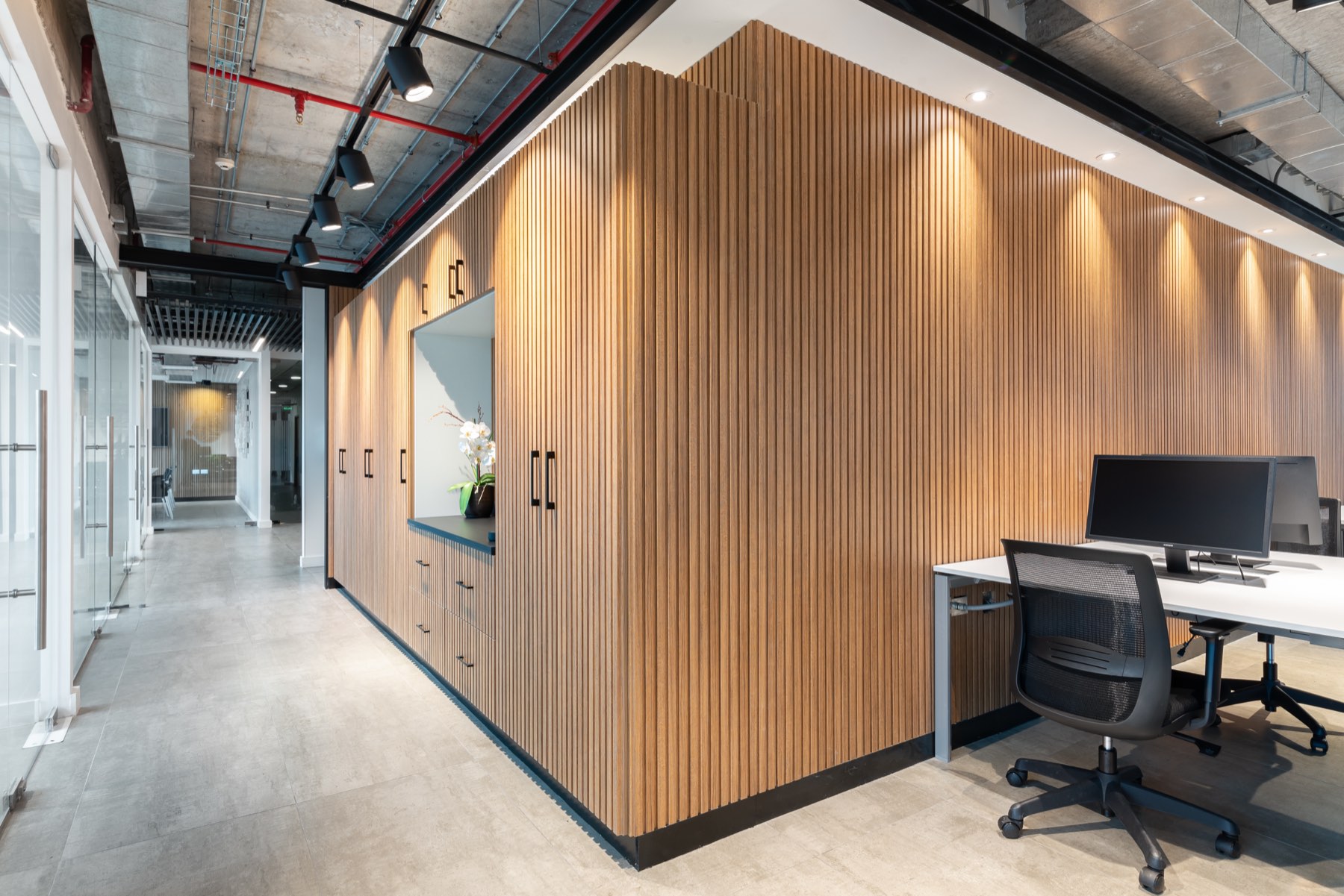 Pasillo interior con muro de listones de madera y puestos de trabajo